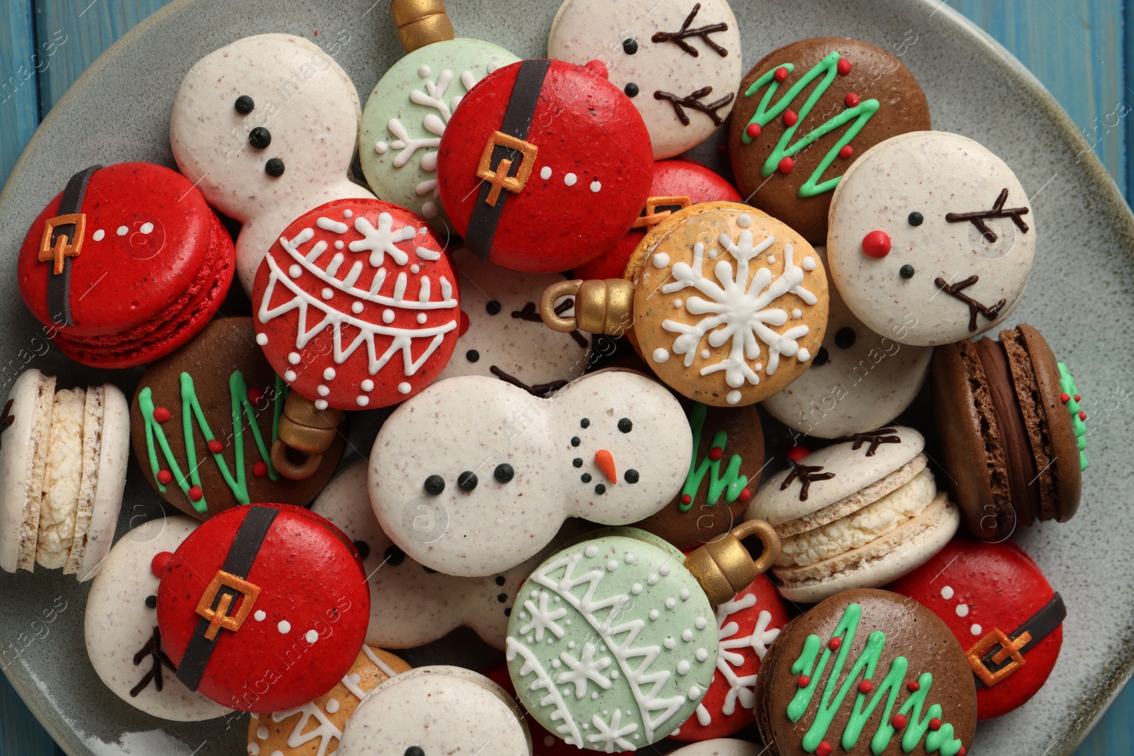 Photo of Beautifully decorated Christmas macarons on light blue table, top view