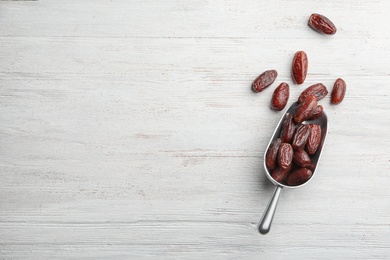 Photo of Scoop with sweet dried date fruits on wooden background, top view. Space for text