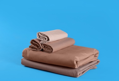 Photo of Stack of clean bed sheets on blue background