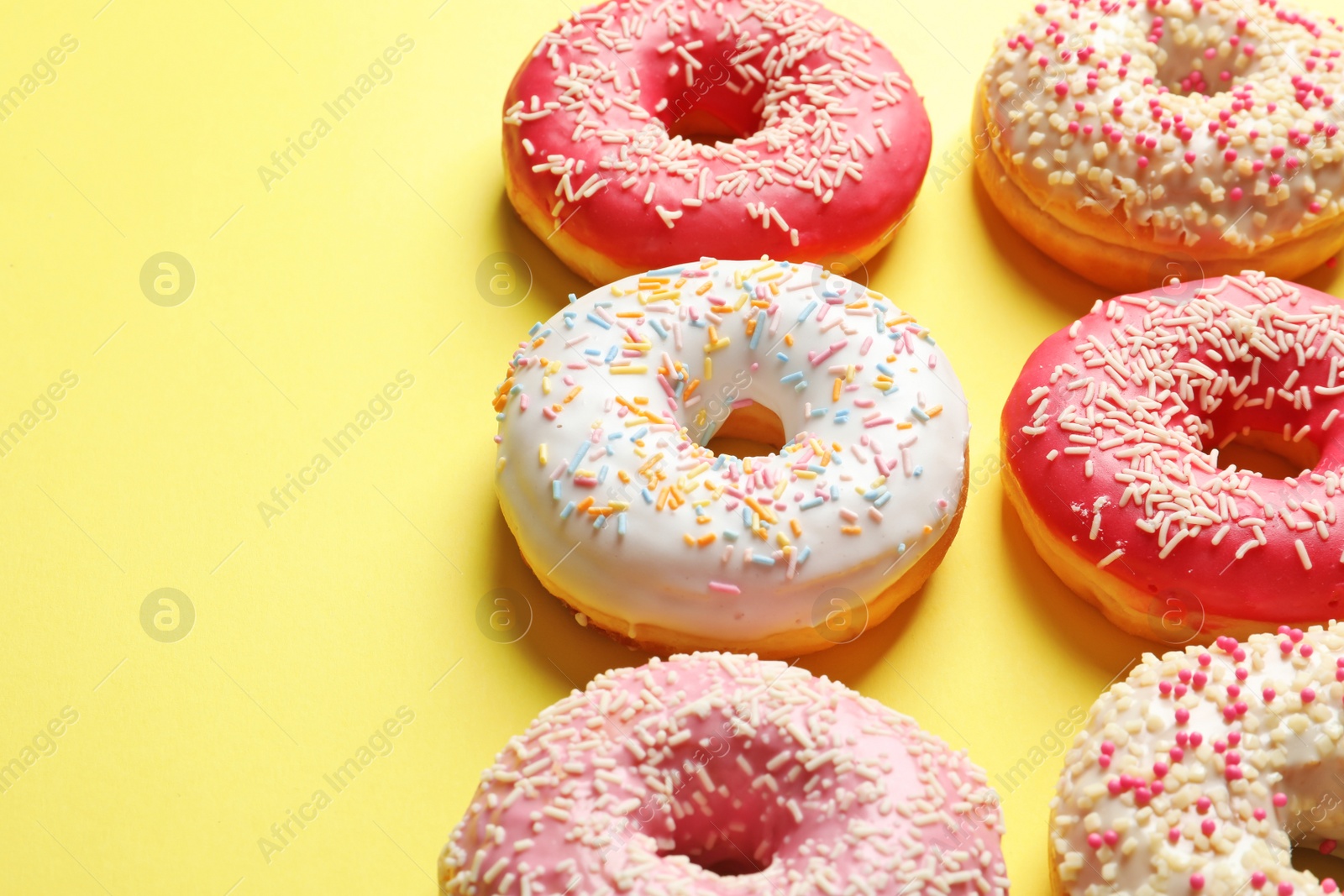 Photo of Delicious glazed doughnuts with sprinkles on color background