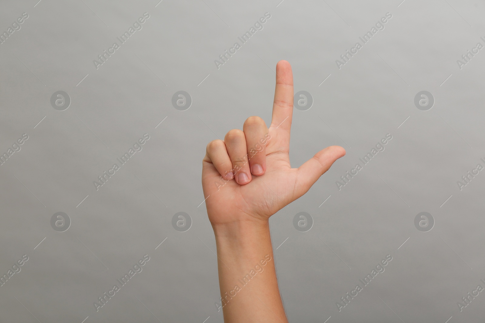 Photo of Teenage boy pointing at something on light grey background, closeup
