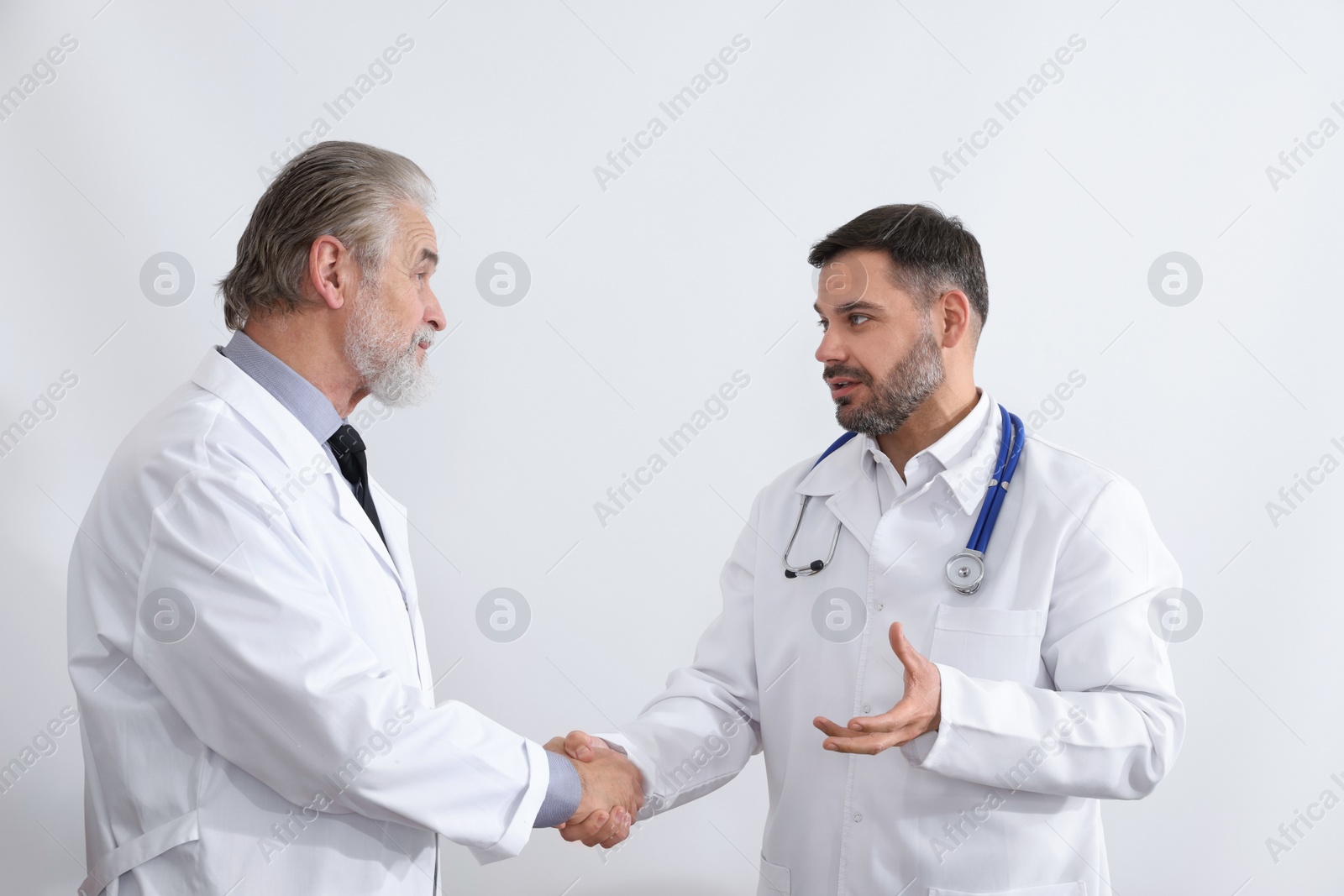 Photo of Doctors shaking hands on white background. Medical conference