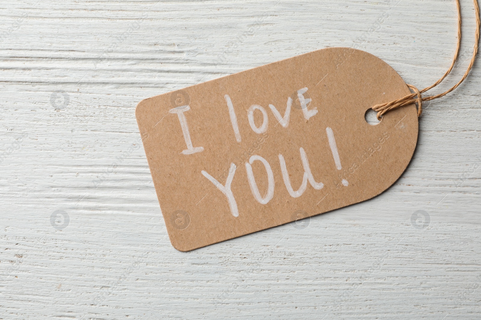 Photo of Tag with words I LOVE YOU on wooden background, top view