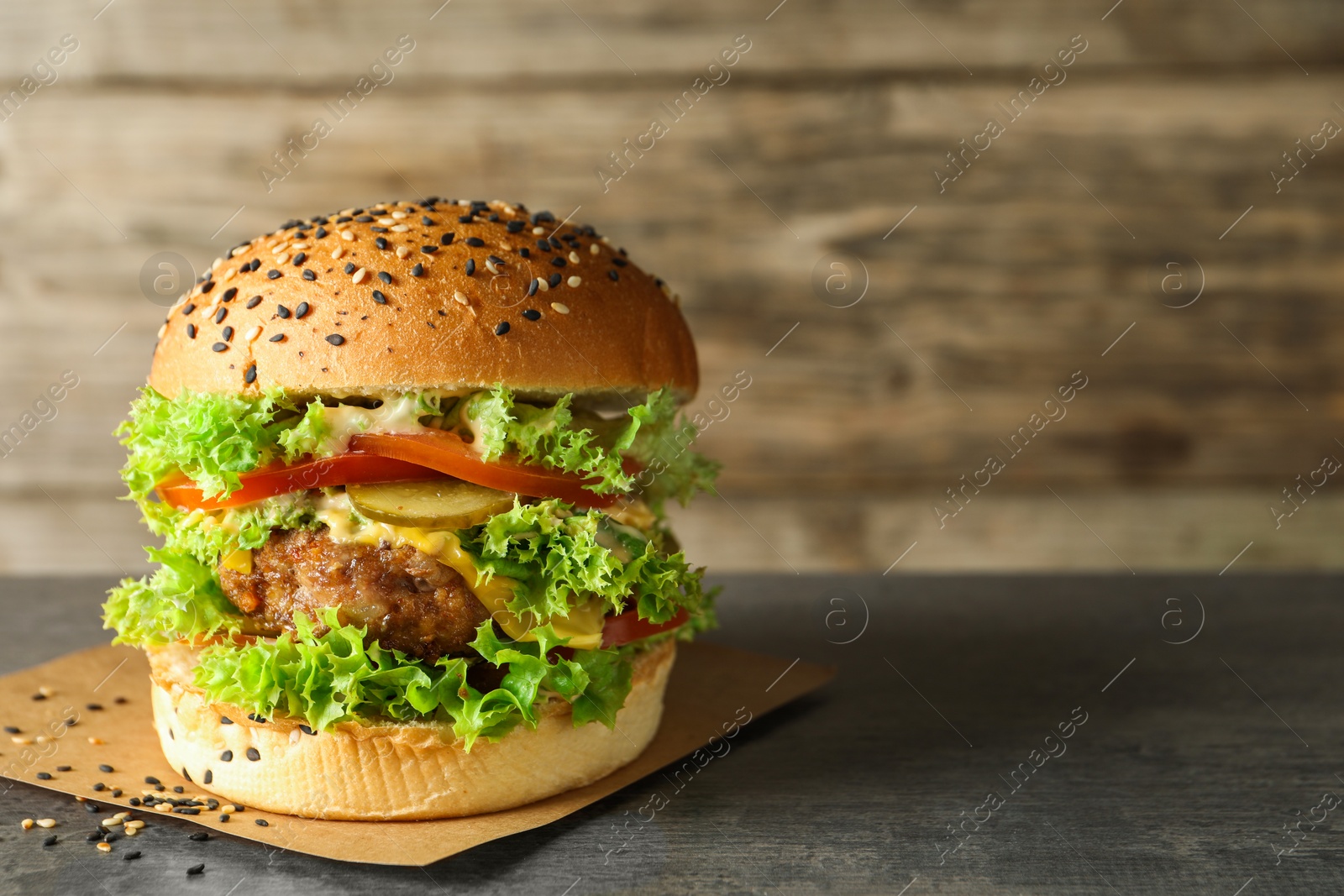 Burger with delicious patty on gray table, space for text Photo of Burger with delicious patty on gray table, space for text