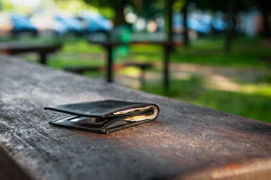 Photo of Black wallet on bench outdoors. Lost and found