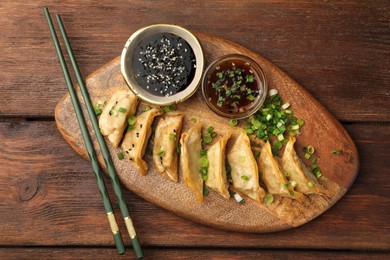 Photo of Delicious gyoza (asian dumplings) served on wooden table, top view