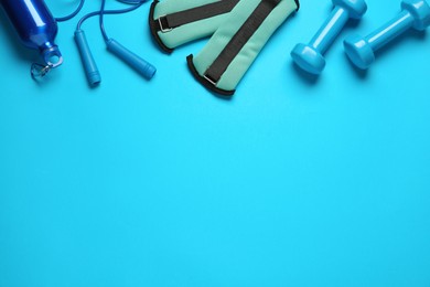 Photo of Turquoise weighting agents and sport equipment on light blue background, flat lay. Space for text