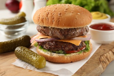 Tasty hamburger with patties, cheese and vegetables served on white table, closeup