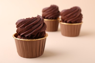 Delicious chocolate cupcakes on beige background, closeup