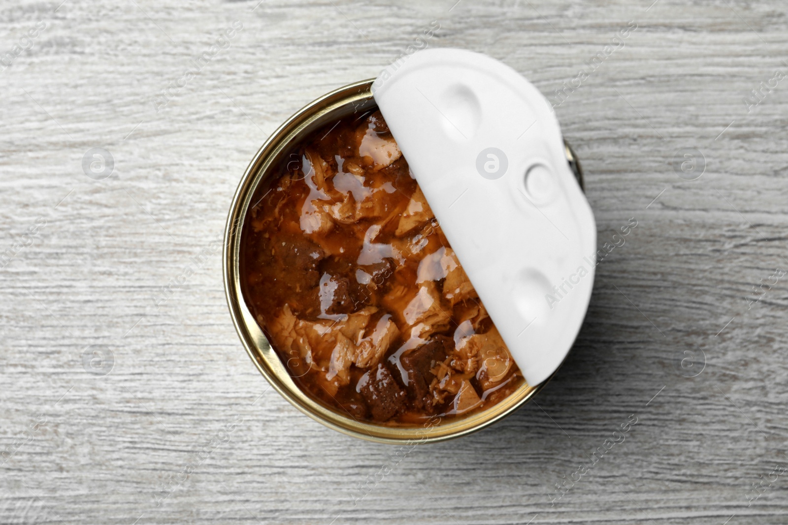 Photo of Tin can of wet pet food on white wooden table, top view