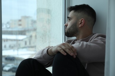 Sad man looking at window at home