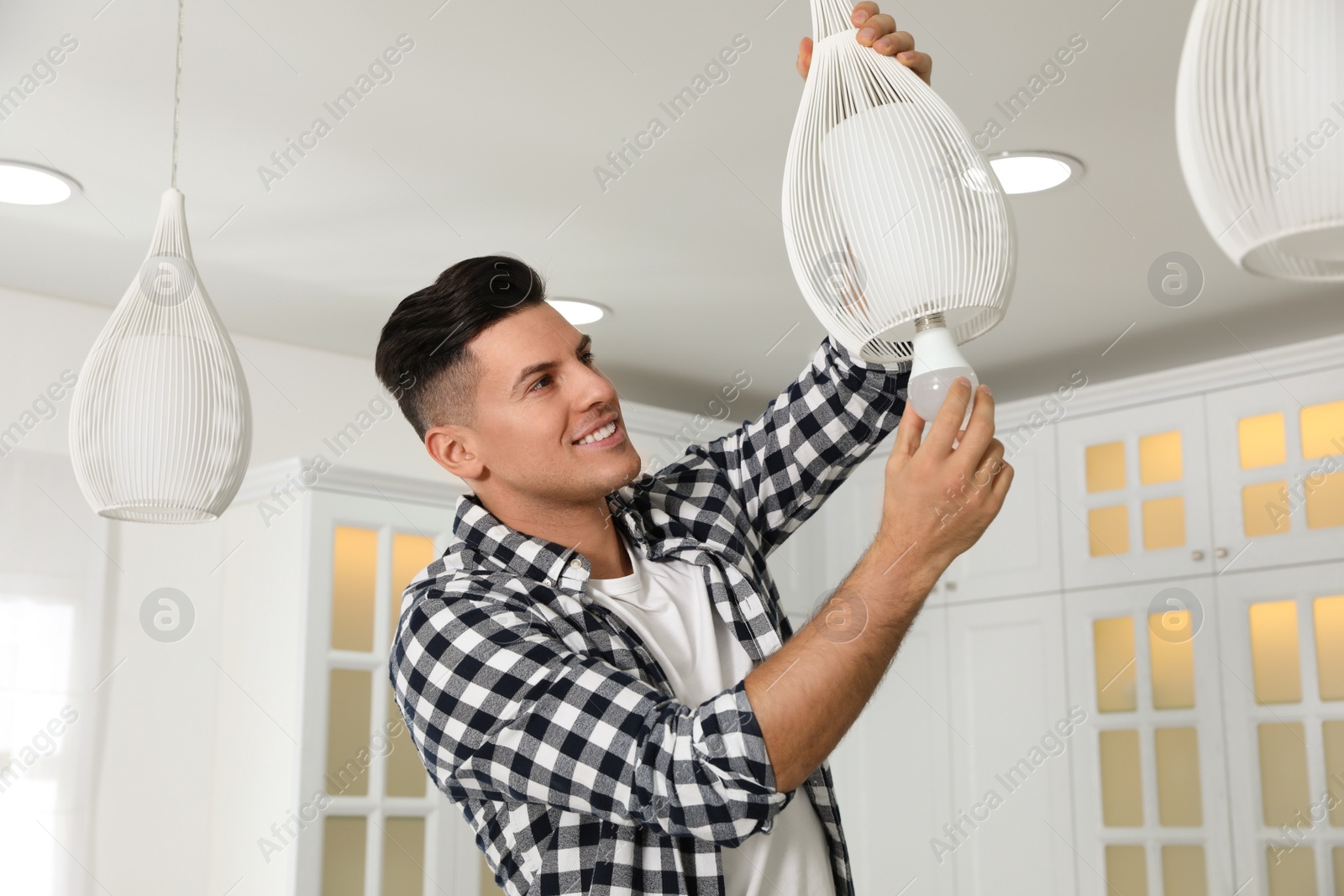 Photo of Man changing light bulb in lamp at home