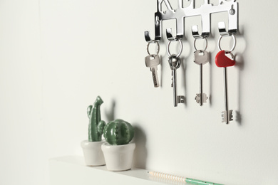 Photo of Metal key holder on light wall indoors
