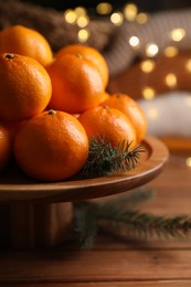 Photo of Stand with delicious ripe tangerines and fir twigs on wooden table