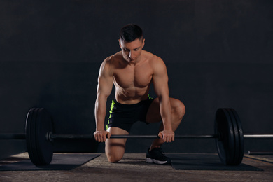 Strong man lifting barbell in modern gym