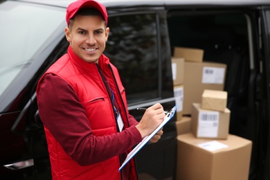Photo of Courier checking amount of parcels in delivery van outdoors. Space for text