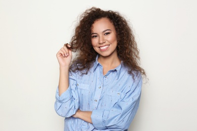 Young African-American woman with beautiful face on light background