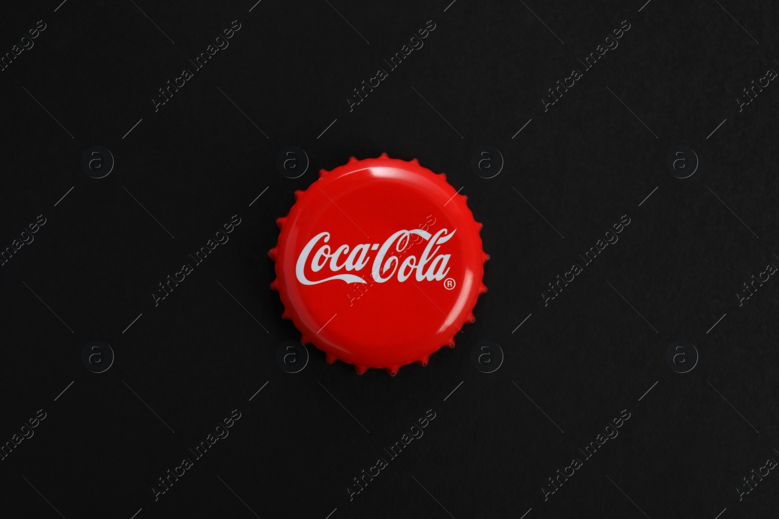 Photo of MYKOLAIV, UKRAINE - NOVEMBER 15, 2018: Coca Cola lid on black background, top view