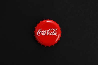 Photo of MYKOLAIV, UKRAINE - NOVEMBER 15, 2018: Coca Cola lid on black background, top view