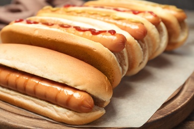 Tasty hot dogs on wooden board, closeup