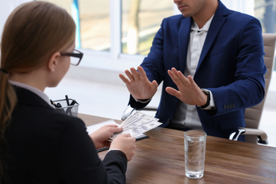 Businessman refuses to take bribe money at wooden table, closeup