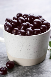 Photo of Fresh acai berries in mug on light grey table, closeup