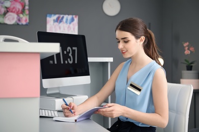 Photo of Beauty salon receptionist with notebook at desk