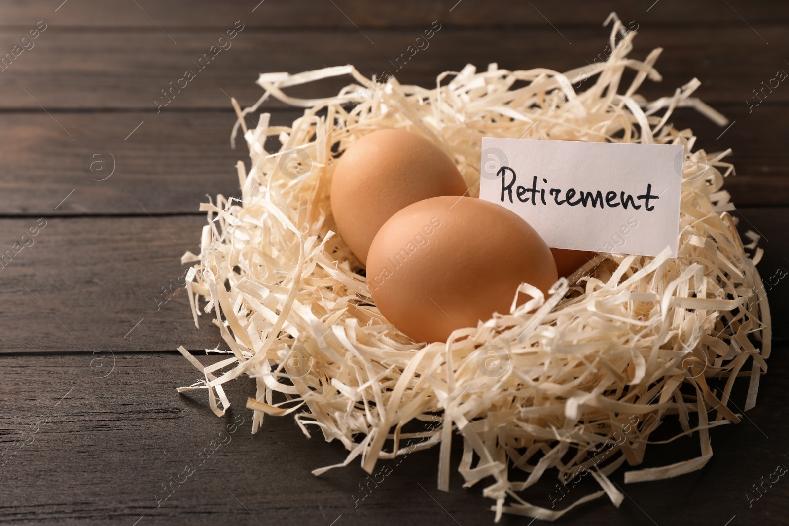 Photo of Eggs and card with word RETIREMENT in nest on wooden background. Pension concept