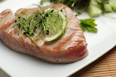 Photo of Delicious tuna steak with microgreens and lime on plate, closeup