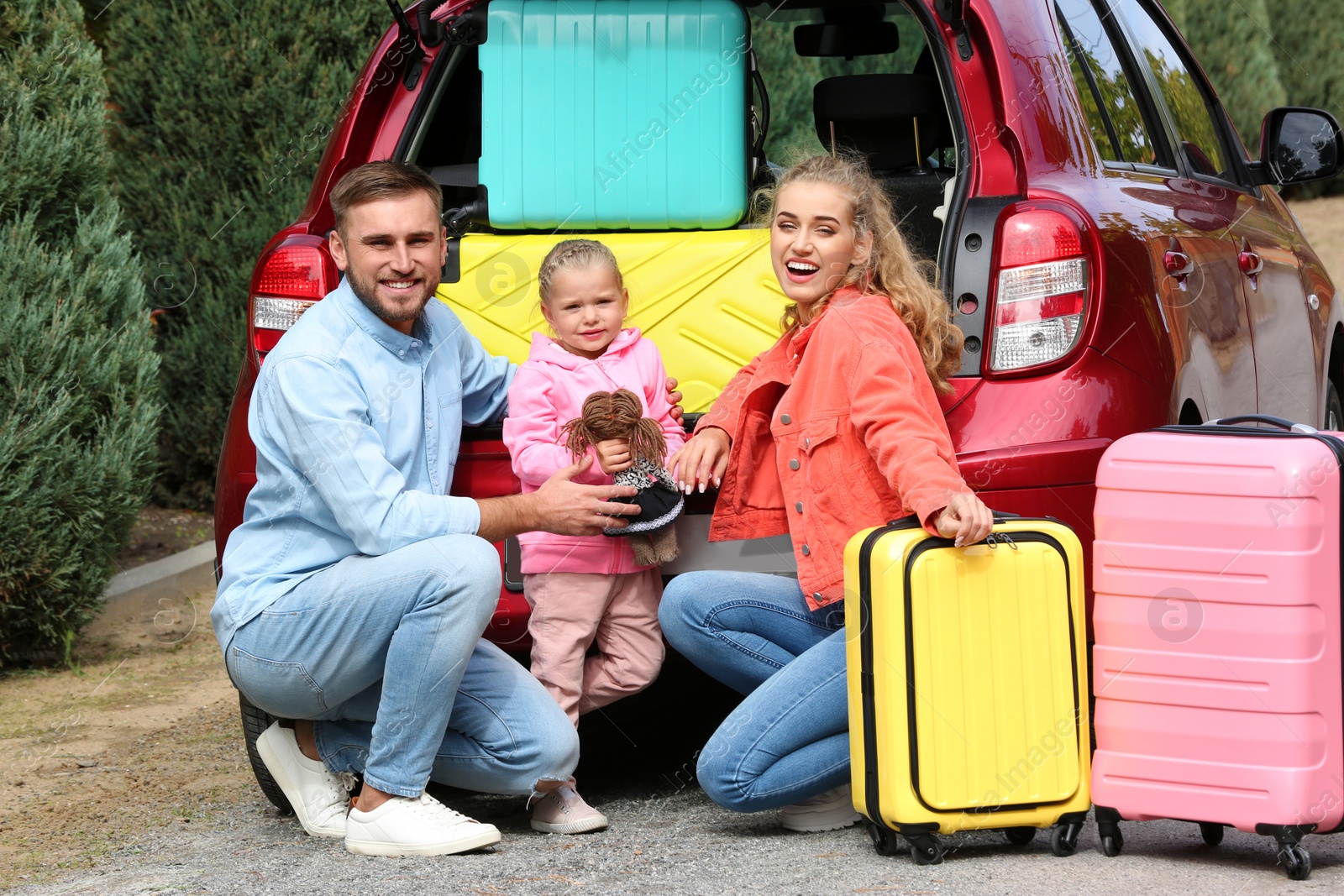 Photo of Young family with suitcases near car trunk outdoors