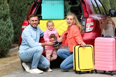 Young family with suitcases near car trunk outdoors