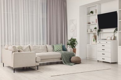Photo of Stylish living room interior with comfortable sofa, TV set and houseplant