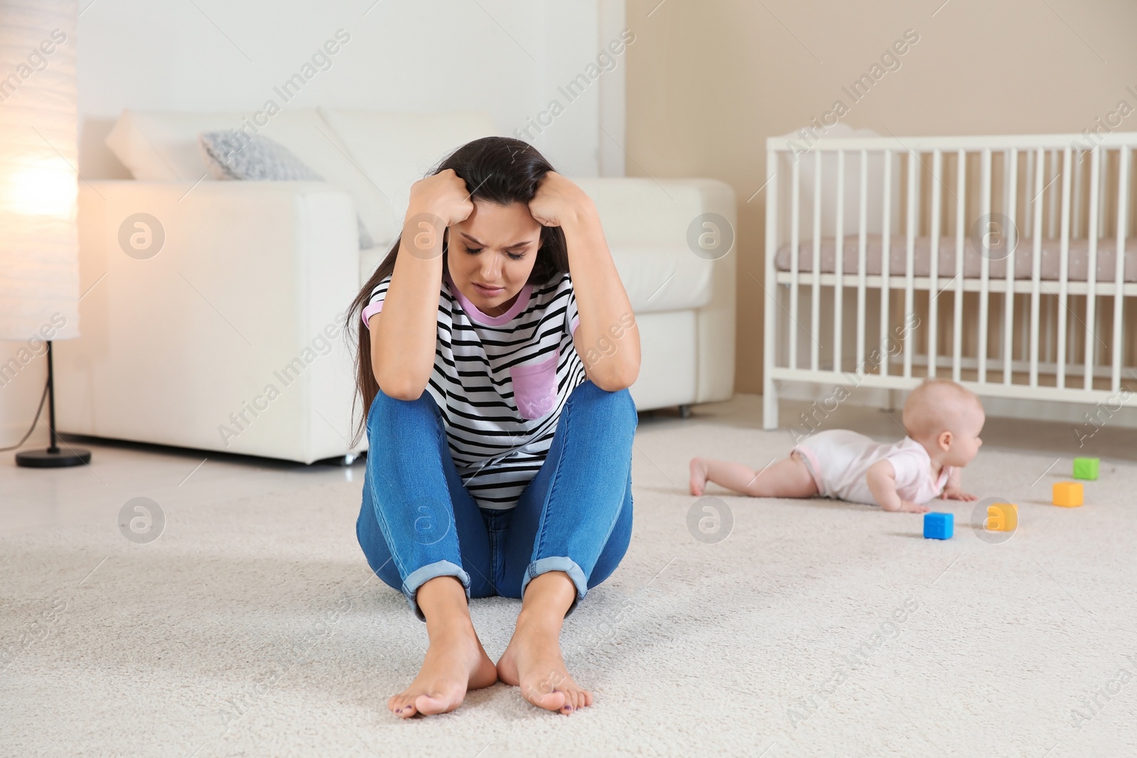 Photo of Young mother suffering from postnatal depression and little baby in room