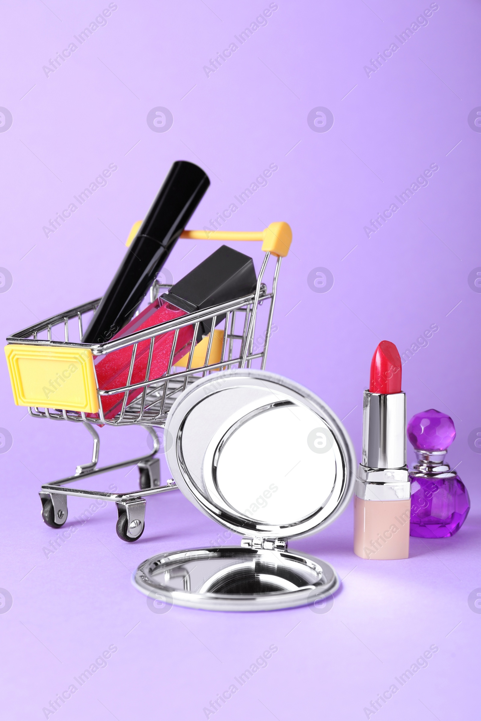 Photo of Stylish pocket mirror and makeup products on lilac background