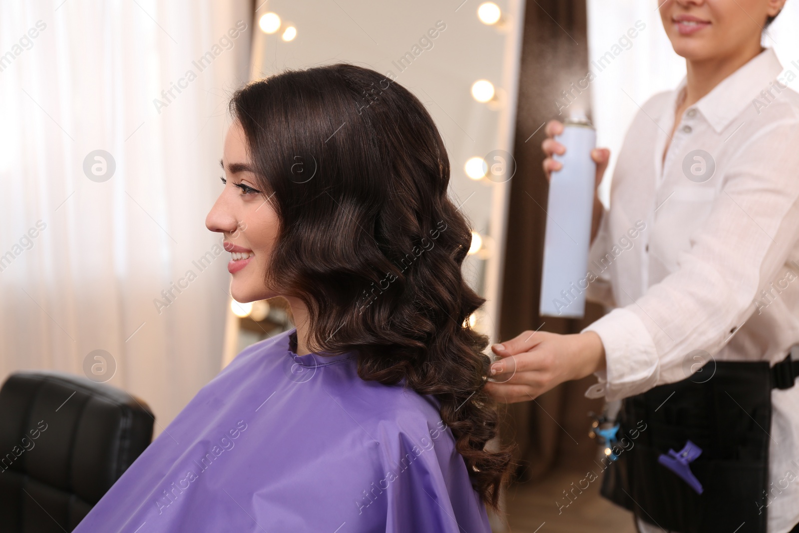 Photo of Stylist working with client in salon, making hairstyle