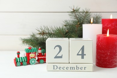 Photo of Christmas Eve - December 24. Block calendar and festive decor on white wooden table