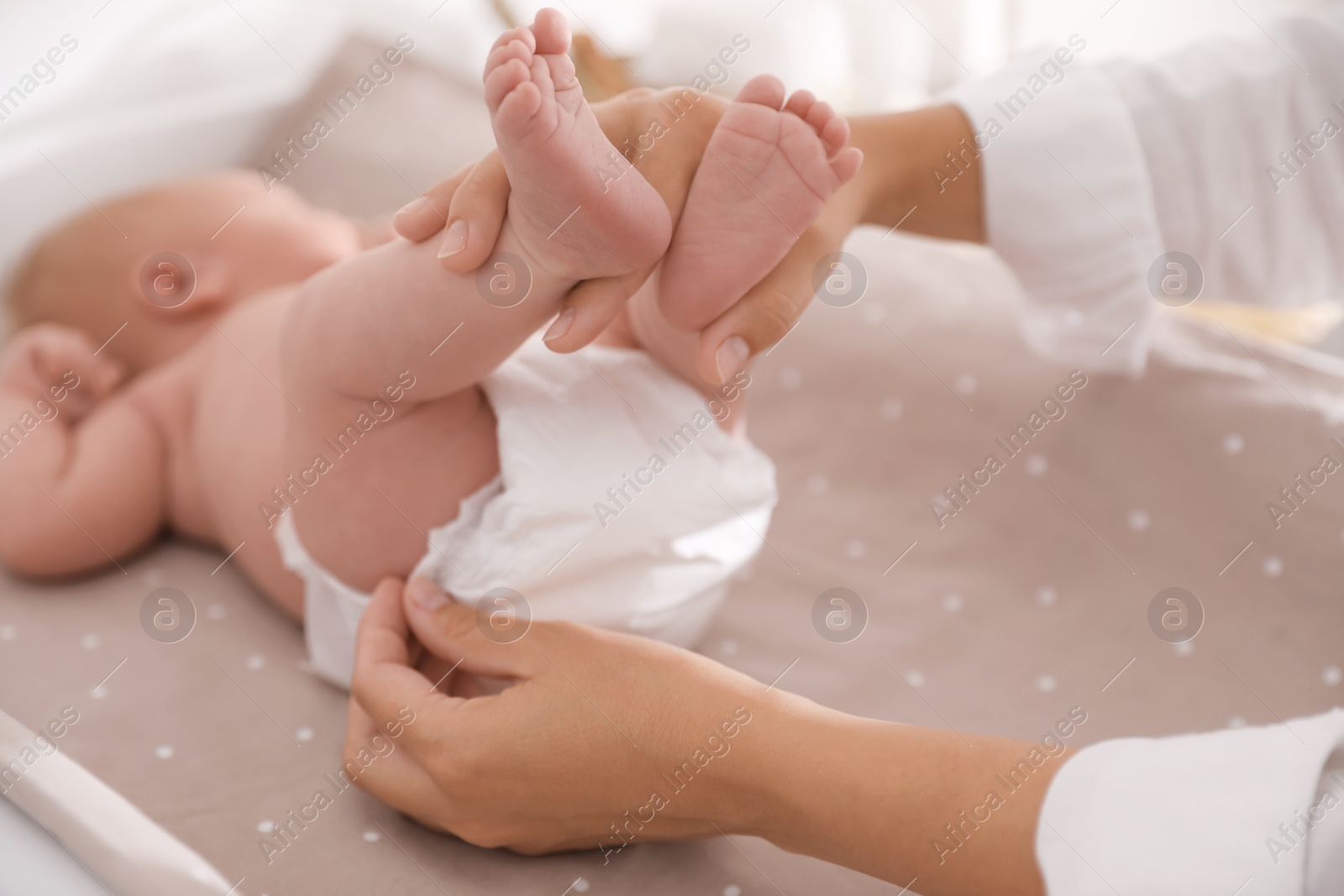 Photo of Mother changing her baby's diaper on table, closeup