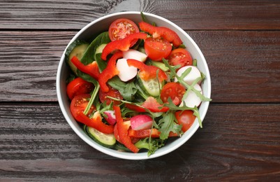 Photo of Tasty fresh vegetarian salad on dark wooden table, top view