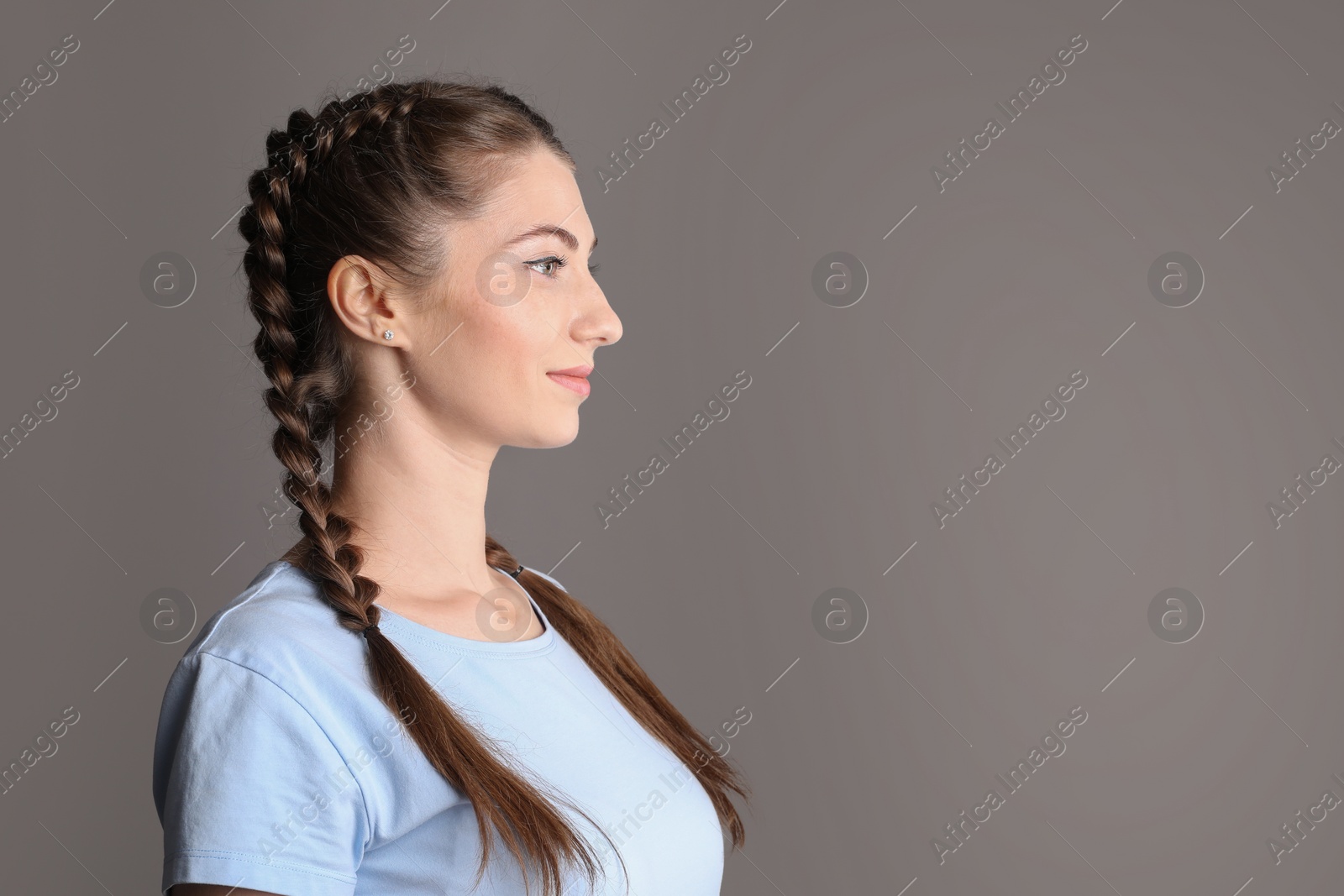 Photo of Woman with braided hair on grey background. Space for text