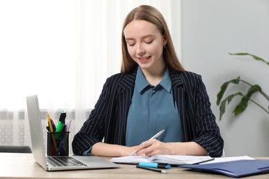 Photo of Woman taking notes at wooden table in office