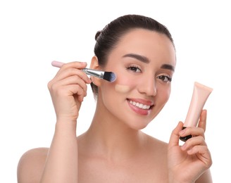 Photo of Woman with tube applying foundation on face using brush against white background