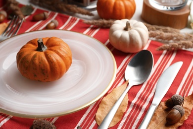 Photo of Autumn table setting with pumpkins on red striped fabric, closeup