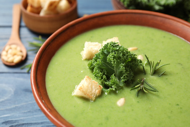 Photo of Tasty kale soup with croutons on table, closeup