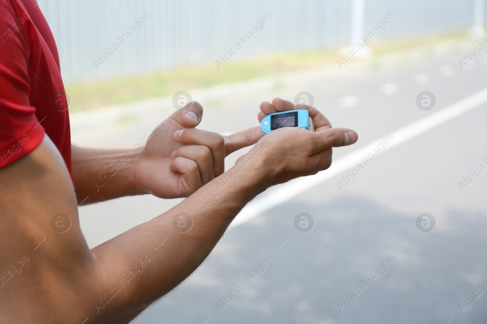 Photo of Young man checking pulse with medical device after training, closeup