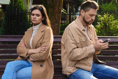 Upset arguing couple sitting on bench in park. Relationship problems