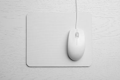 Photo of Wired computer mouse and pad on white wooden background, flat lay. Space for text