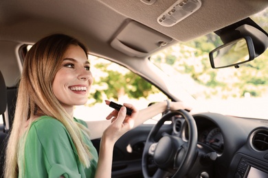 Beautiful careless woman applying makeup in car