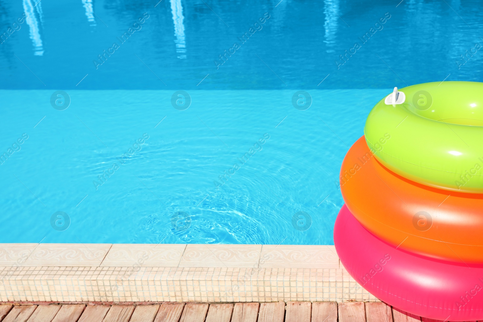 Photo of Modern swimming pool with inflatable rings outdoors. Space for text