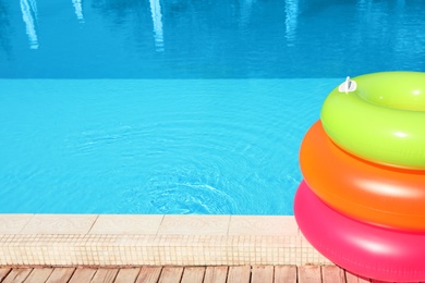 Photo of Modern swimming pool with inflatable rings outdoors. Space for text