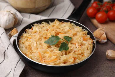 Frying pan with sauerkraut on brown table